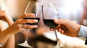 Male and female hands toasting wine glasses.